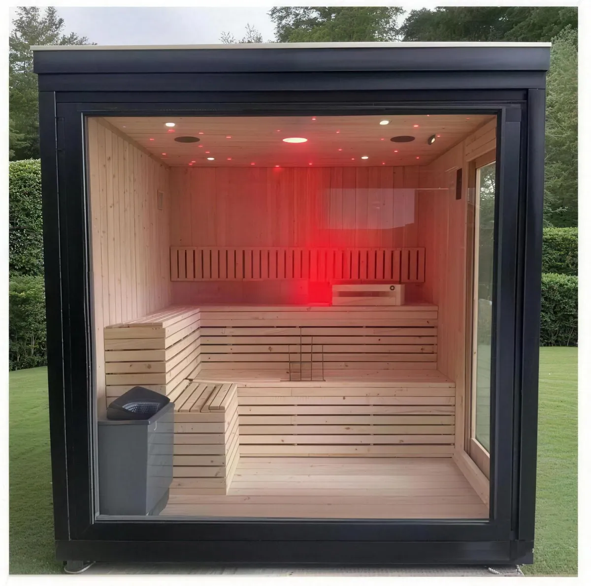 Outdoor sauna kaca panorama dengan bingkai hitam, bangku hemlock dan pemanas elektrik di atas rumput